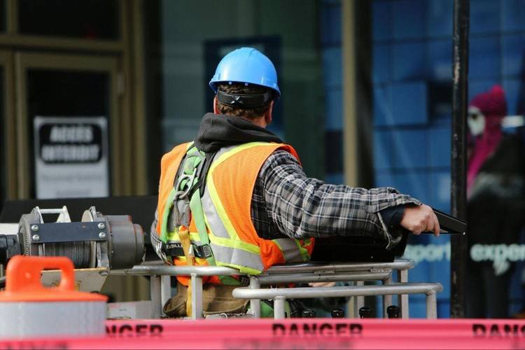 Trabalhador de construção civil usando equipamento de segurança, observando a obra em ambiente urbano